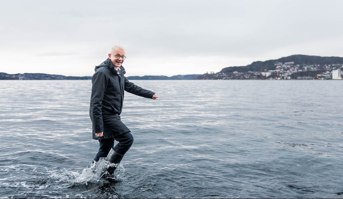 
smilende mann i støvler vasser i sjøen