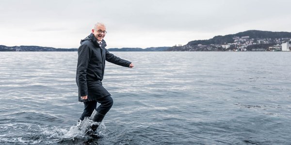 

smilende mann i støvler vasser i sjøen