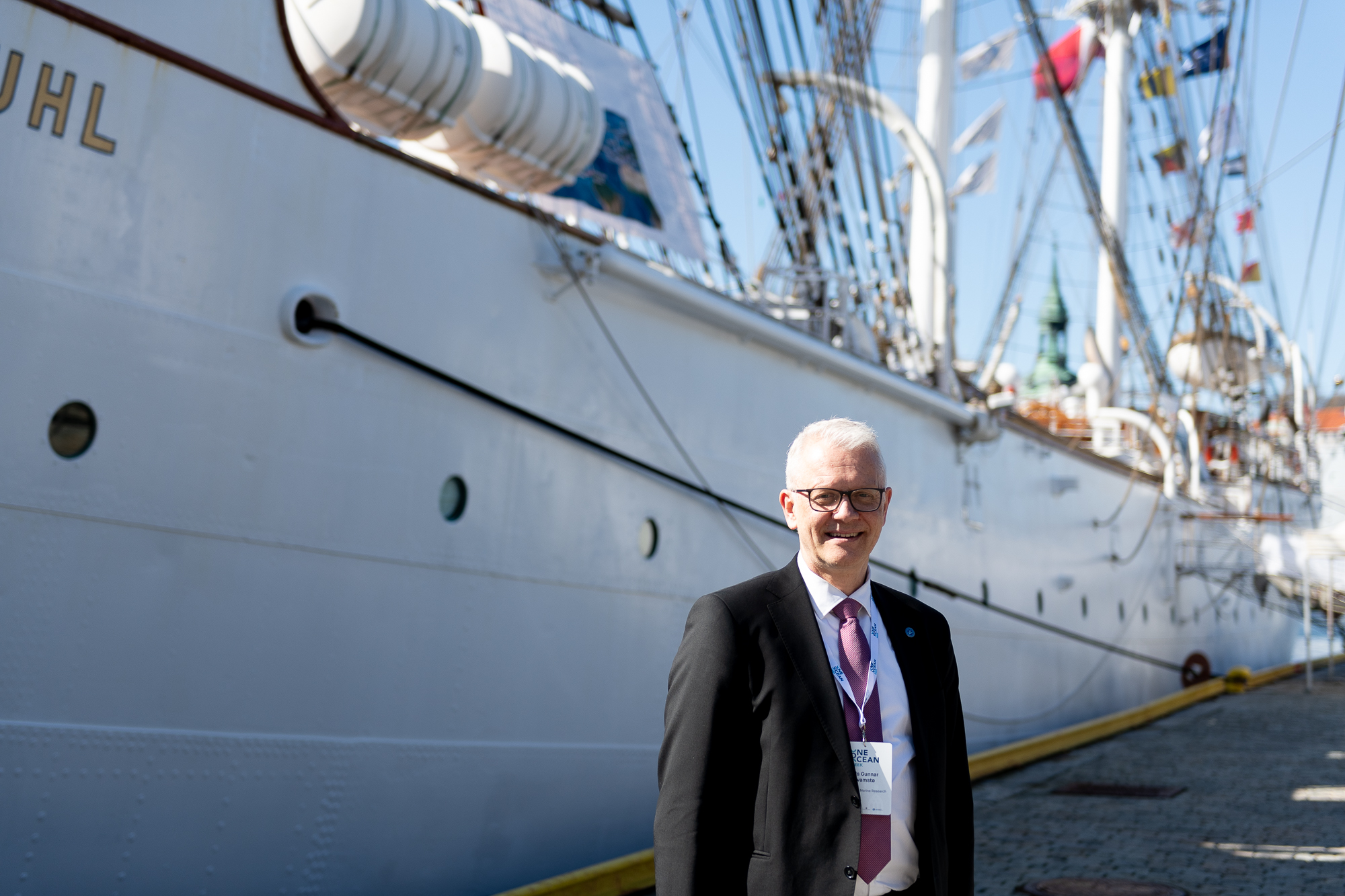 En mann står på kaien. Bak ser en siden på seilskipet Statsraad Lehmkuhl