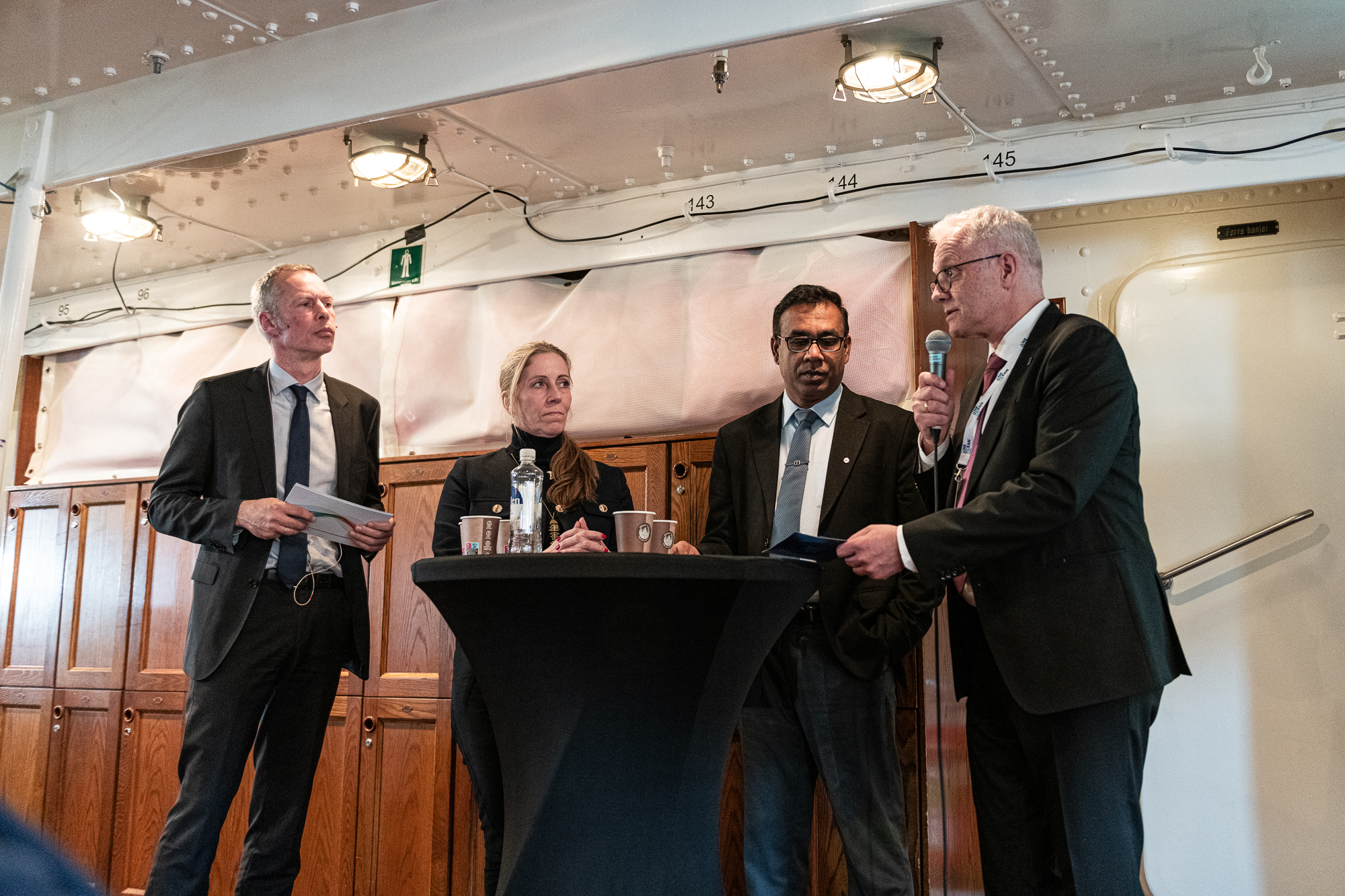 Fire personer i en panelsamtale rundt et høgbord. 