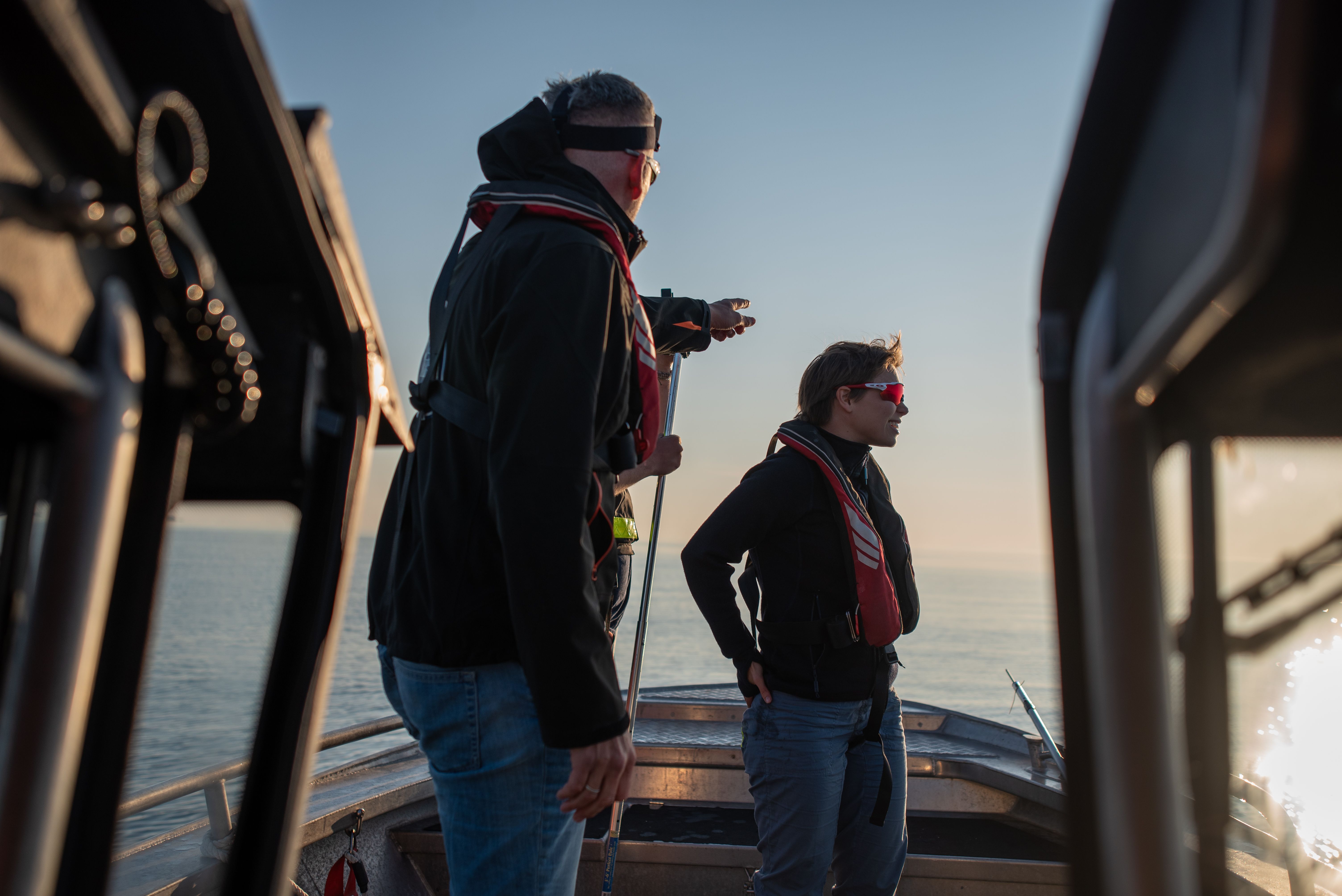 Ein mann og ei kvinne står i ein båt og speidar utover havet.