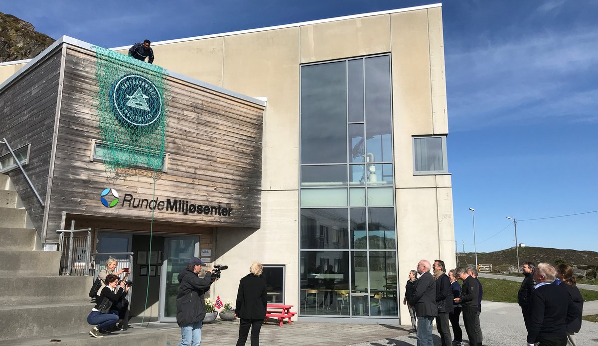 Havforskingsdirektør avdukar logoen til Havforskingsinstituttet over inngangsdøra på Runde miljøsenter.