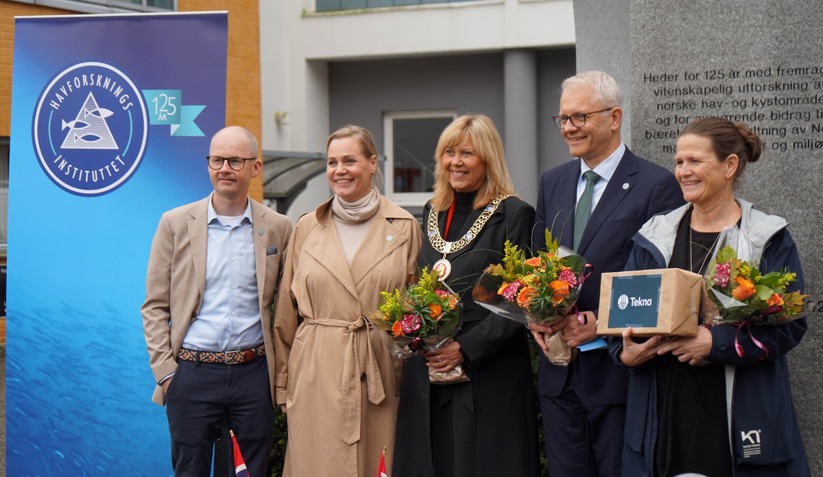 Foto av fem personer foran bauta og rollup med Havforskningsinstituttets logo