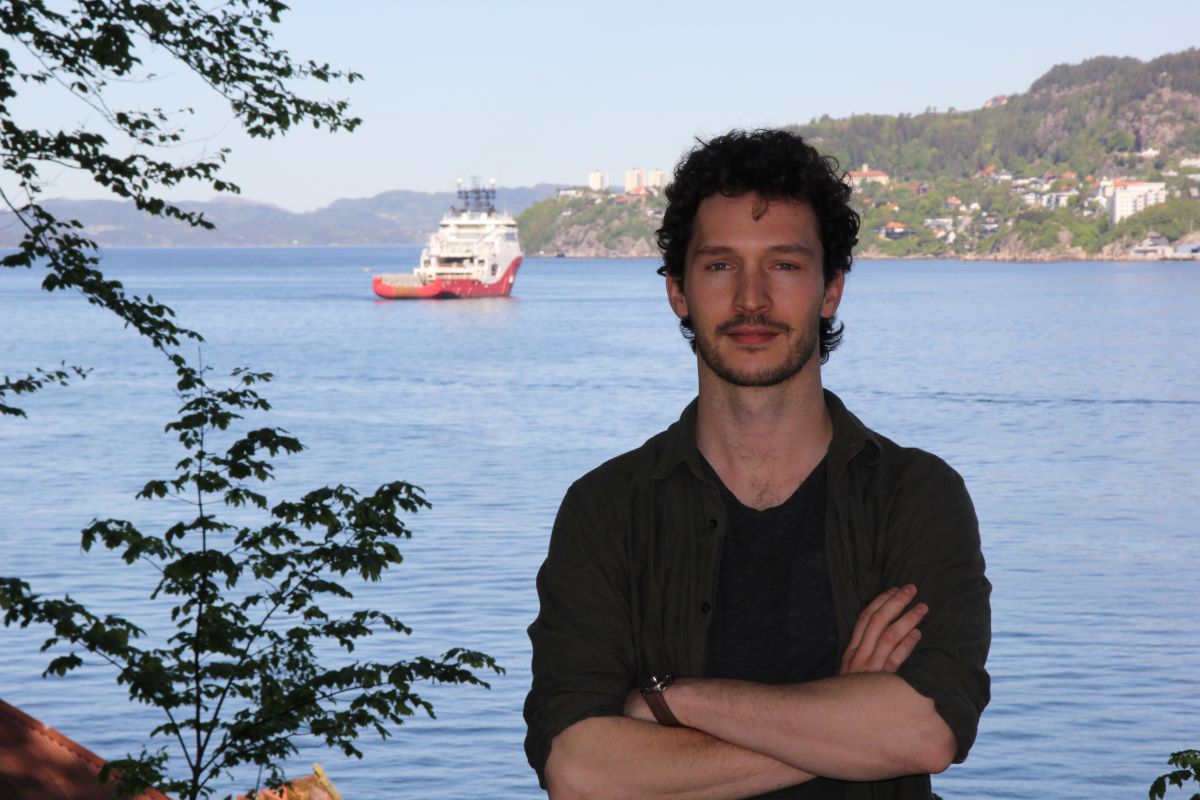 Foto av havforsker Côme Denechaud med sjø og skip i bakgrunnen.