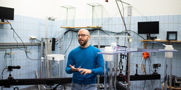 

Man in blue sweater and blue jeans in a room with blue tiles and lots of different equipment.