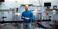 

Man in blue sweater and blue jeans in a room with blue tiles and lots of different equipment.