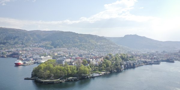 

Oversiktsbilde som viser halvøy med grønne trær, by og fjell i bakgrunnen.