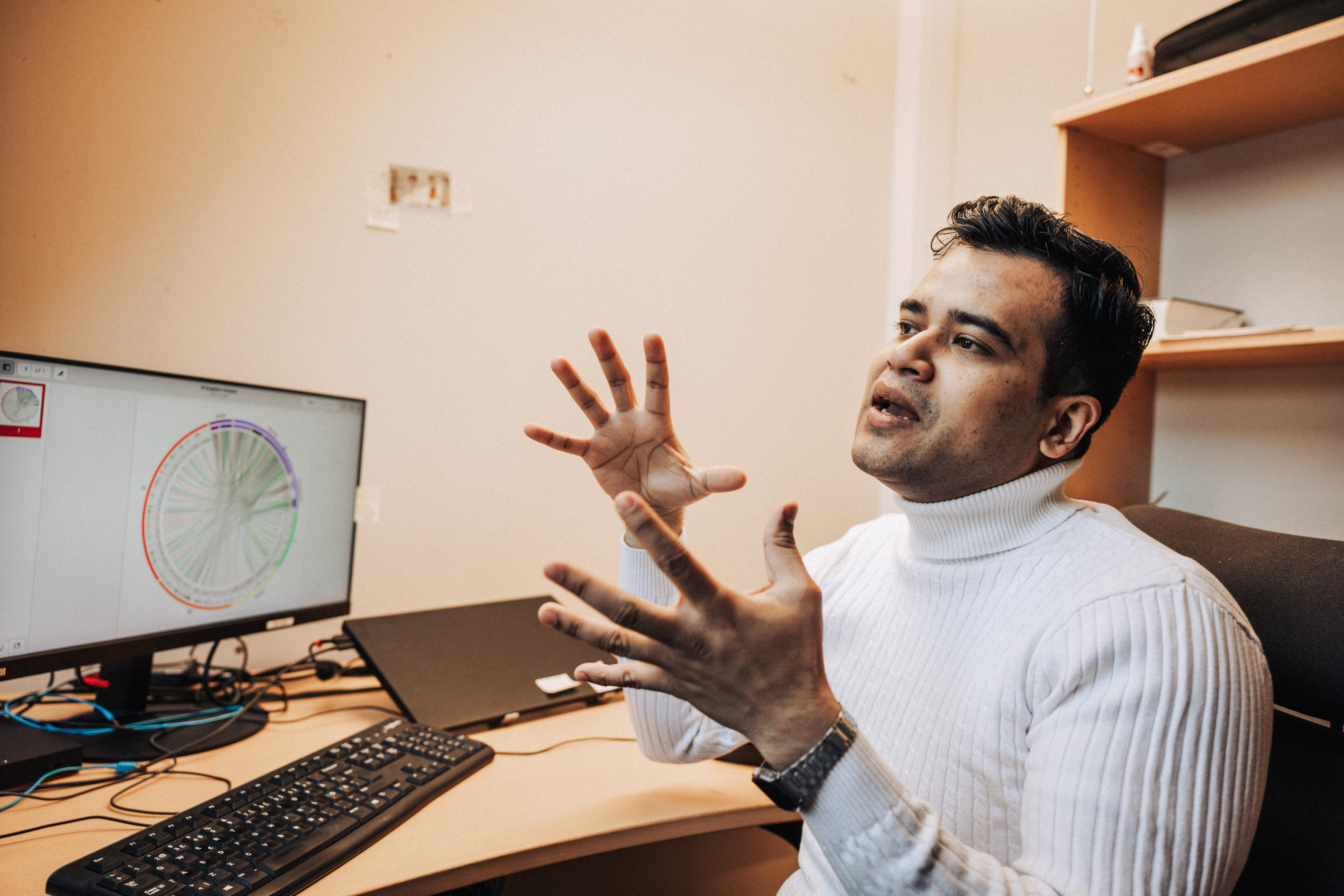 En mann sitter ved kontorpulten sin. Han gestikulerer ivrig med armene