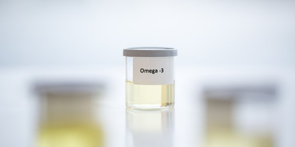Et lite glass med lysegul veske og påklistret lapp der det står «Omega-3.»