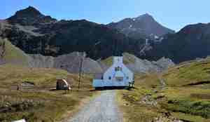 liten hvit kirke med svære, mørke fjell i bakgrunnen