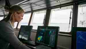 foto av forsker Maria Tenningen som står i styrhuset på et skip og ser på sonar-bildene.