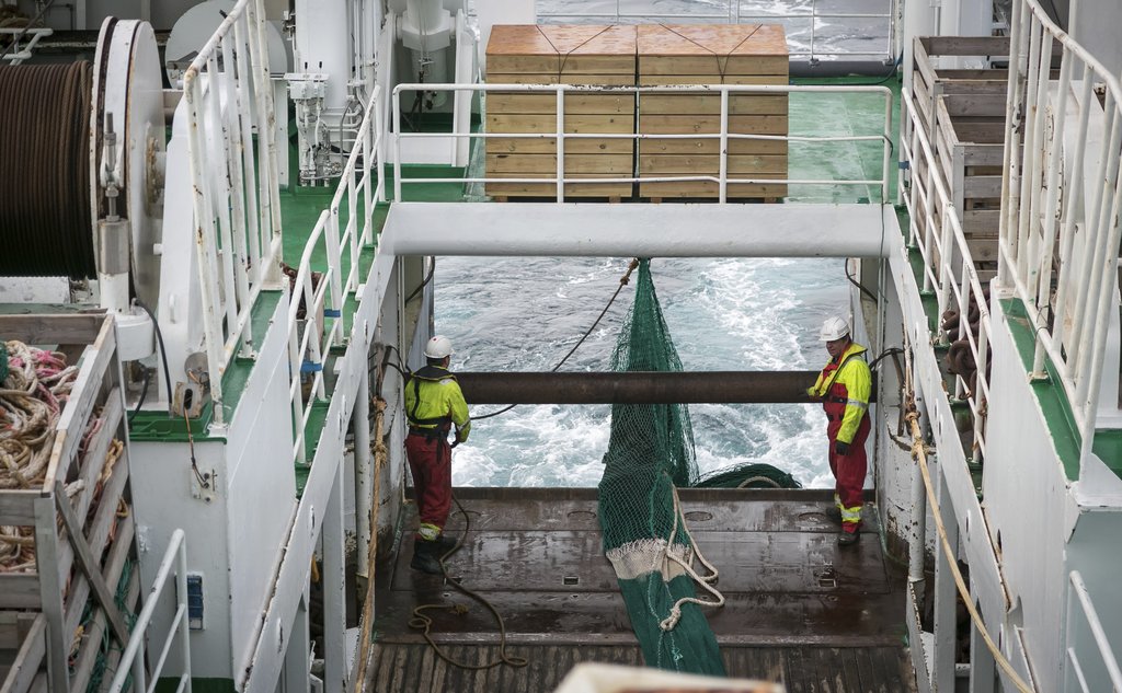 Bilde fra et tråldekk, der to mannskap holder på å slippe ut trålen