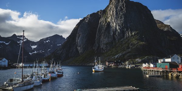 

sjarker til kai med svært spisst fjell i bakgrunnen