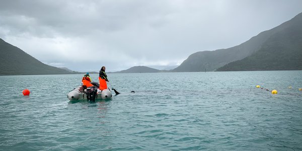 

to personer setter garn i fjorden fra liten gummibåt