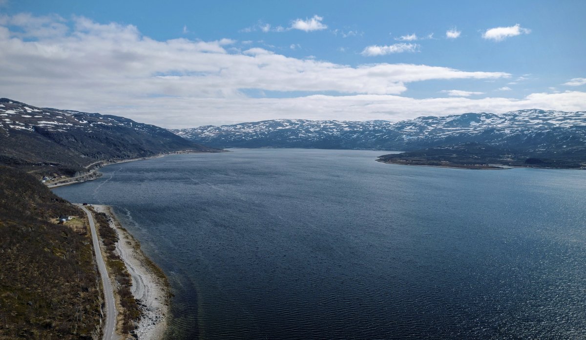 
Dronefoto av fjord med fjell i bakgrunnen