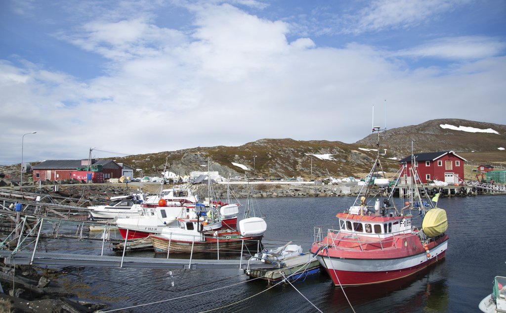Sjarker til kai i nakent, steinete landskap med litt snø i bakgrunnen