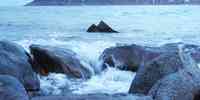 

bølger slår mot grå stein, skummende hvit sjø 
