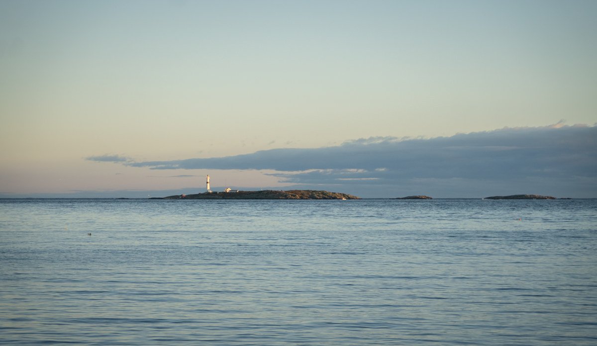 
Utsikt mot kyst og hav i Arendal kommune, Raet nasjonalpark. Den blå himmelen og det blå havet går nesten over i kvarandre, berre bryte opp av Torungen fyr, som ligg på ein holme.