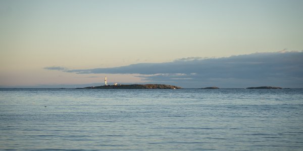 

Utsikt mot kyst og hav i Arendal kommune, Raet nasjonalpark. Den blå himmelen og det blå havet går nesten over i kvarandre, berre bryte opp av Torungen fyr, som ligg på ein holme.