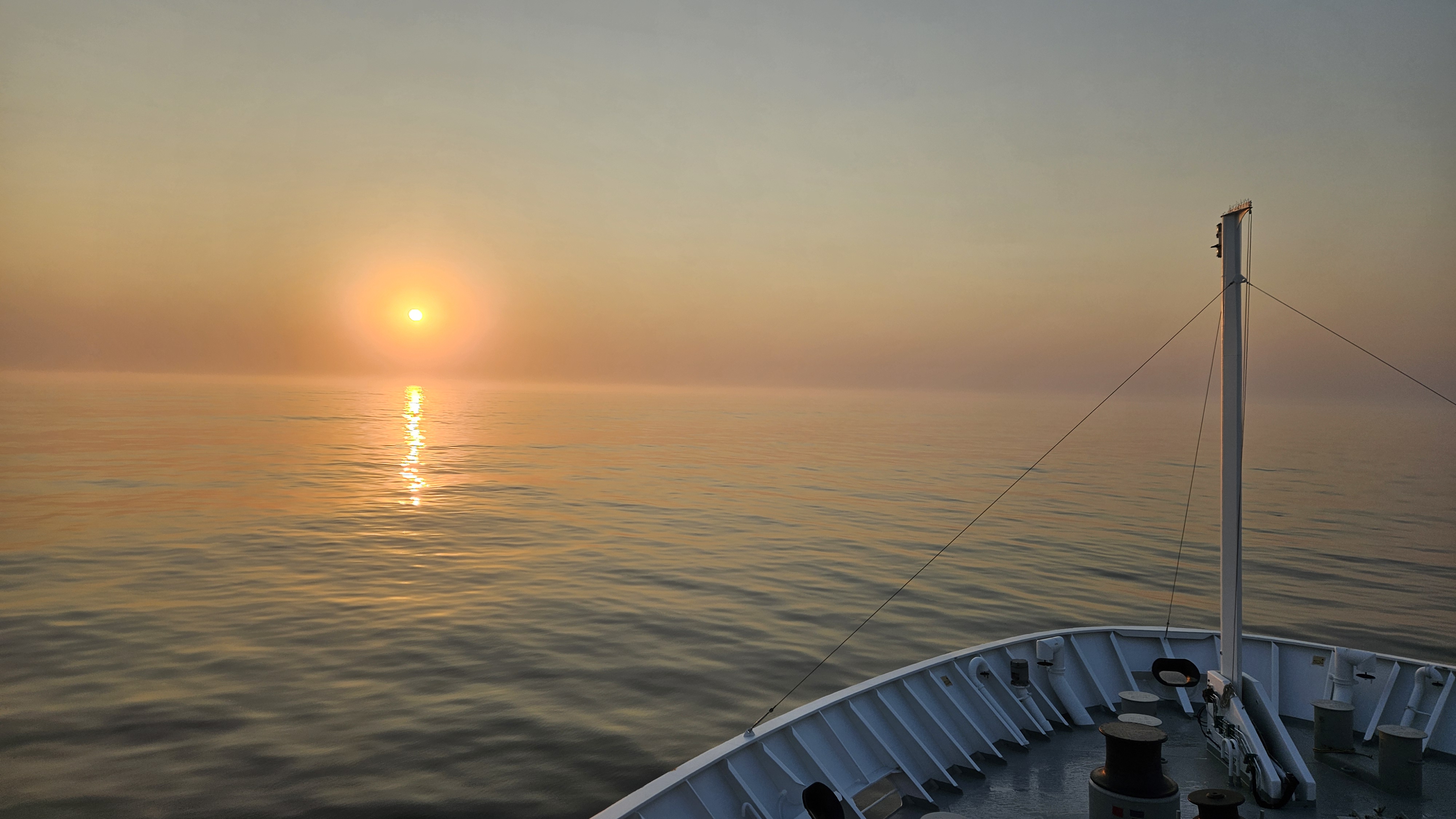 Utsikt frå brua på Nansen. Baugen på båten skimtast så vidt, og sola går ned i horisonten