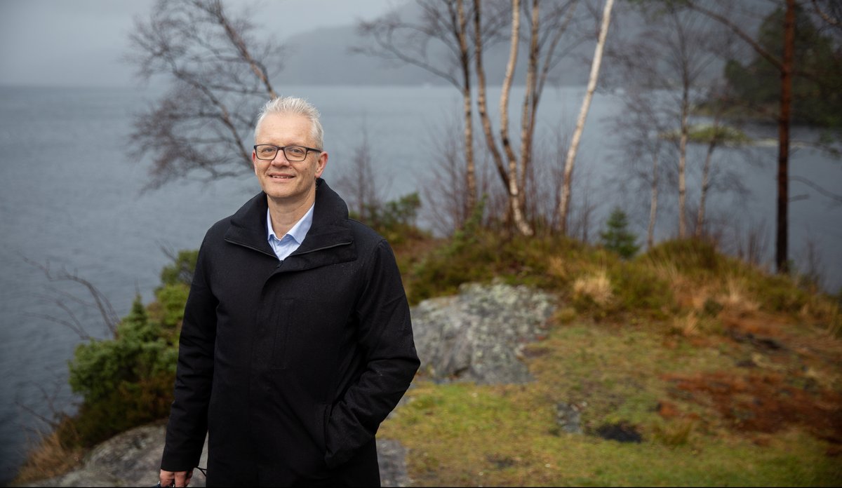 
mann stående på berg med sjø i bakgrunnen