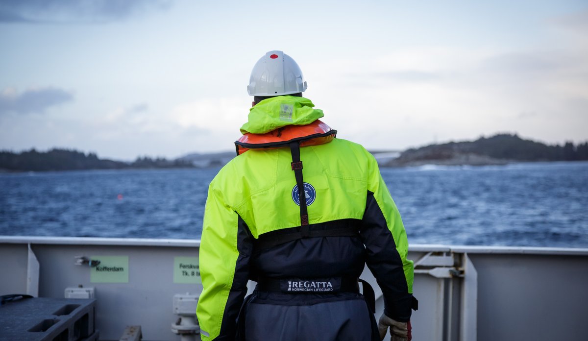 
Havforskar i kjeledress på båt på fjorden, han står med ryggne til.
