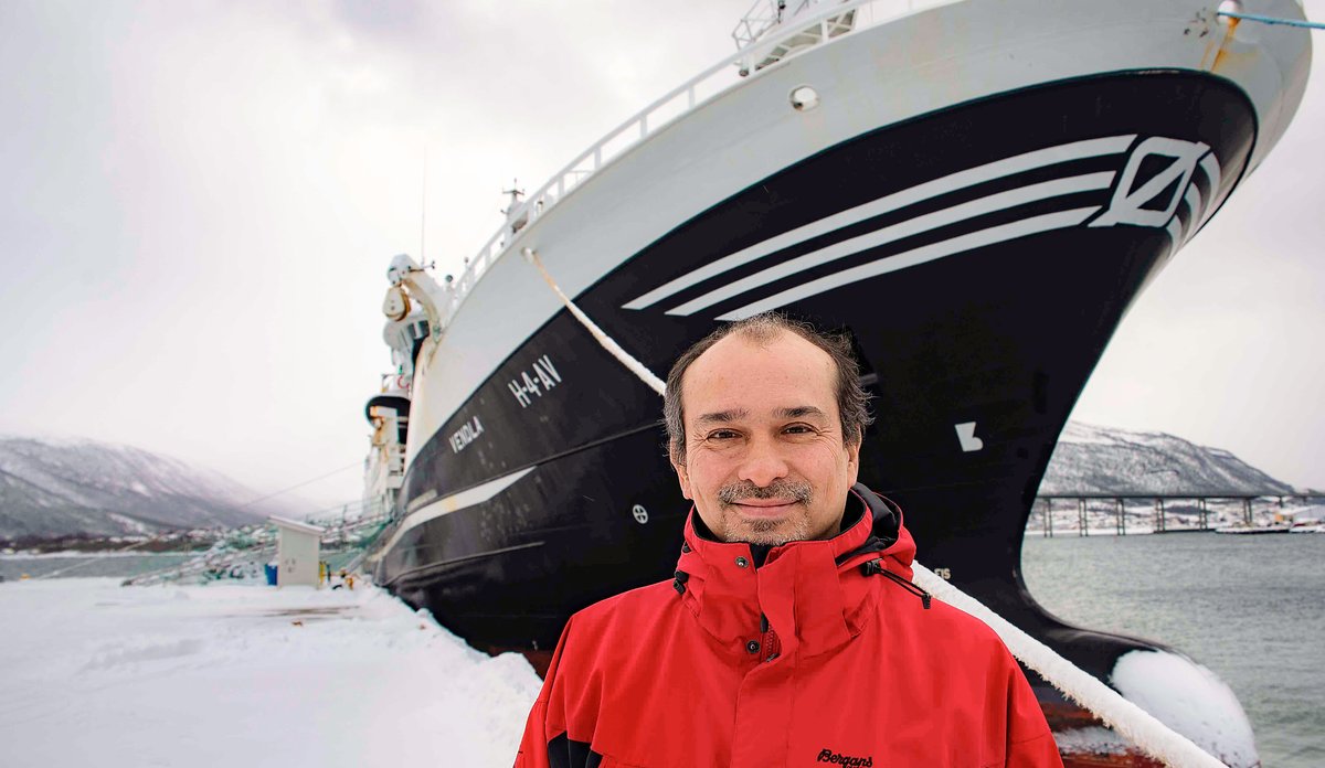 foto av en mann foran en fiskebåt