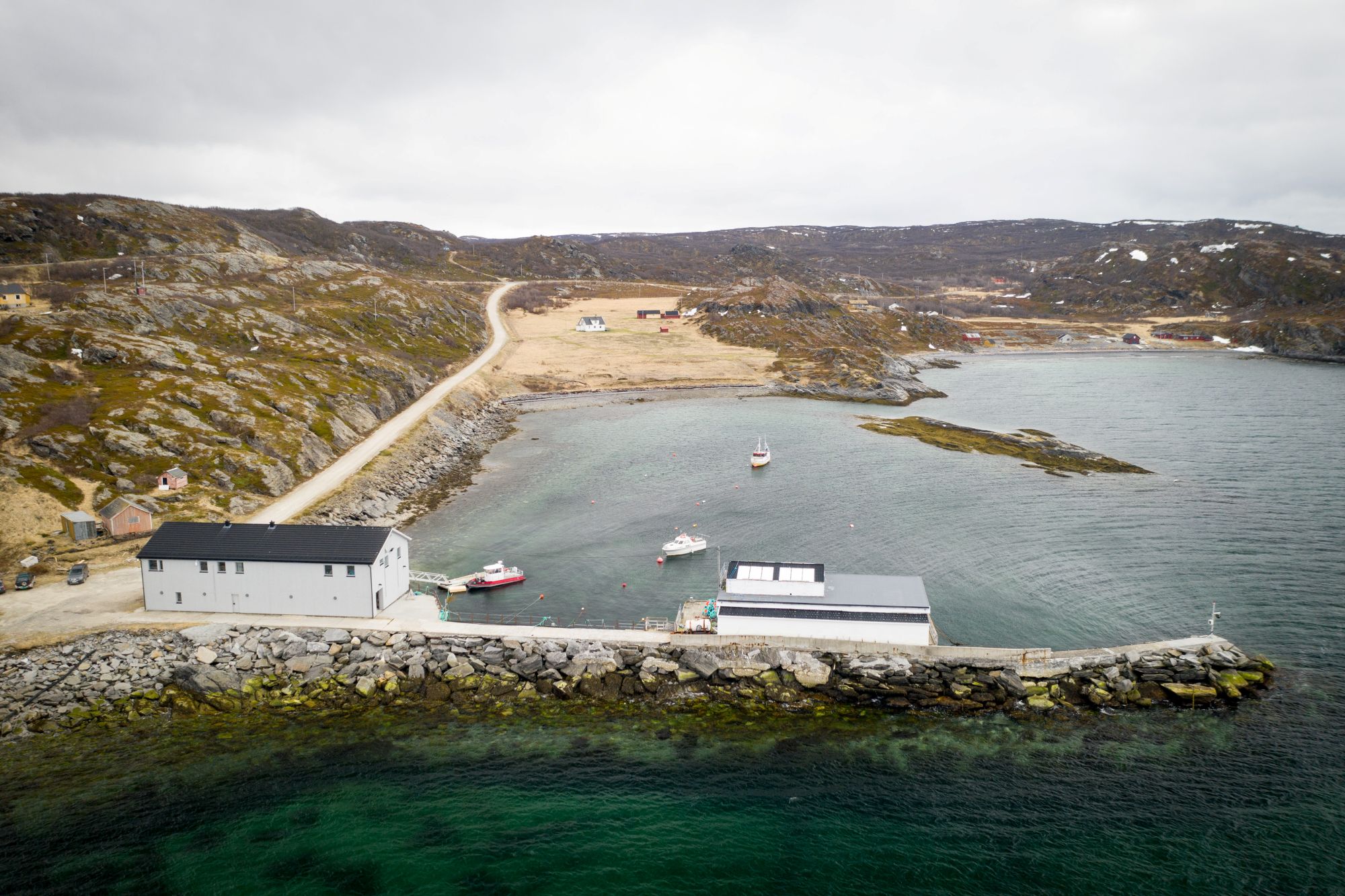 Bilde som viser feltstasjonen til HI i Holmfjord. Det er et stort lagerlignende bygg som ligger ved en molo