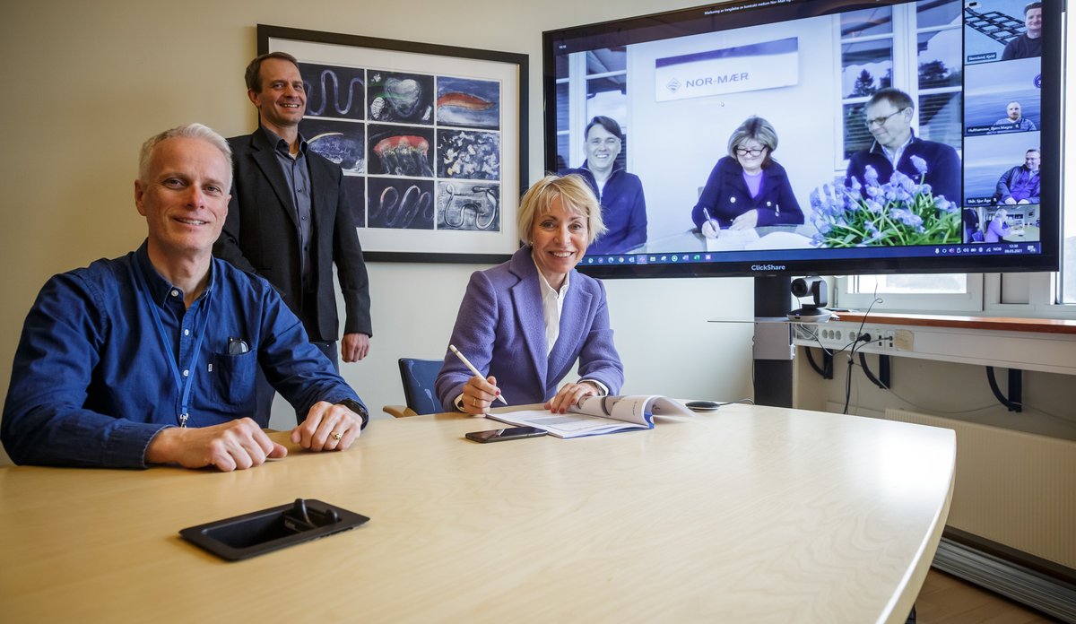 foto av folk som signerer kontrakt, noen på skjerm