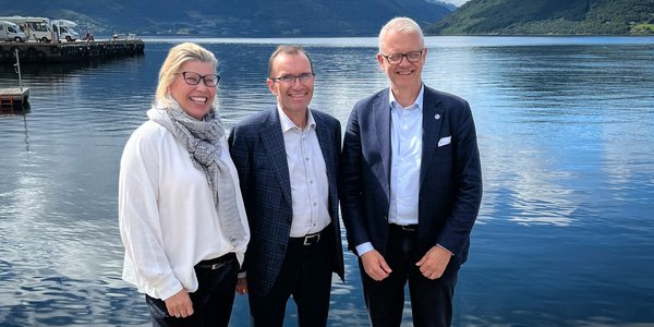

foto av tre personer foran fjorden i Rosendal
