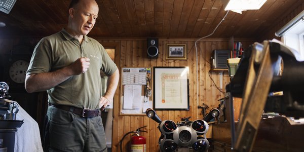 

foto av mann på verksted med en slags robot på et bord