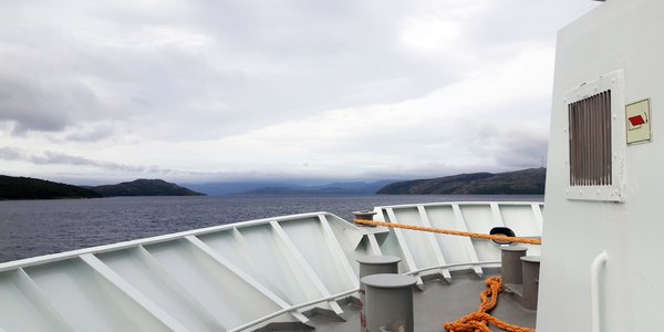 Utsikt fra båtdekk mot sjø og fjell.