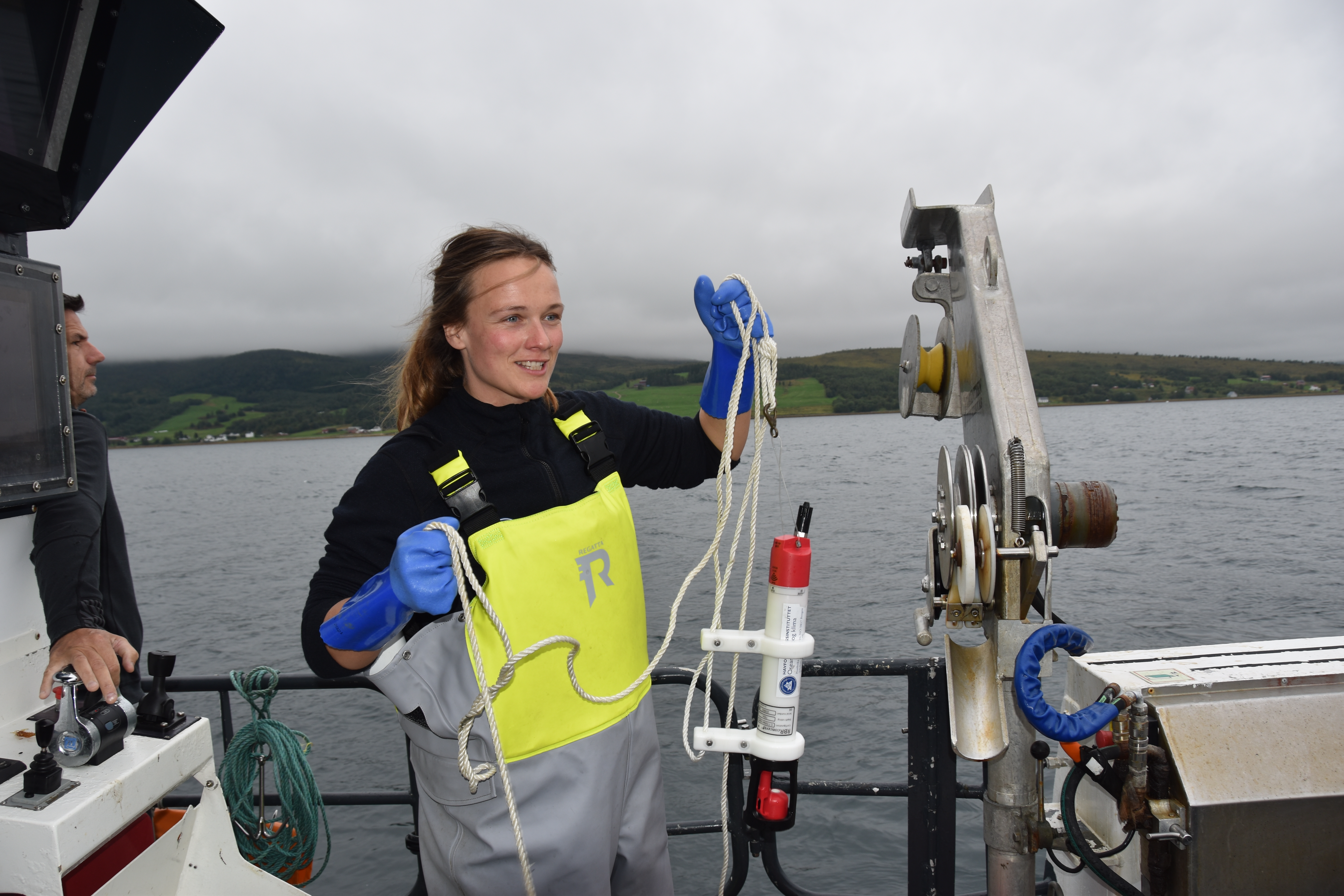 
Stipendiat Johanna holder opp utstyr for å ta vannprøver med, om bord på en båt. 