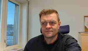 Portrettbilde av forskeren fra brystet og opp med nakkestøtten til stolen i bakgrunnen og et vindu på siden.