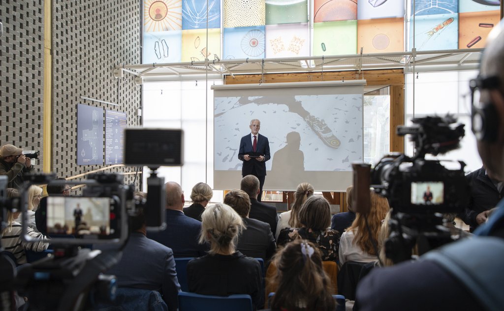 En mann står på en scene framfor en fullsatt sal