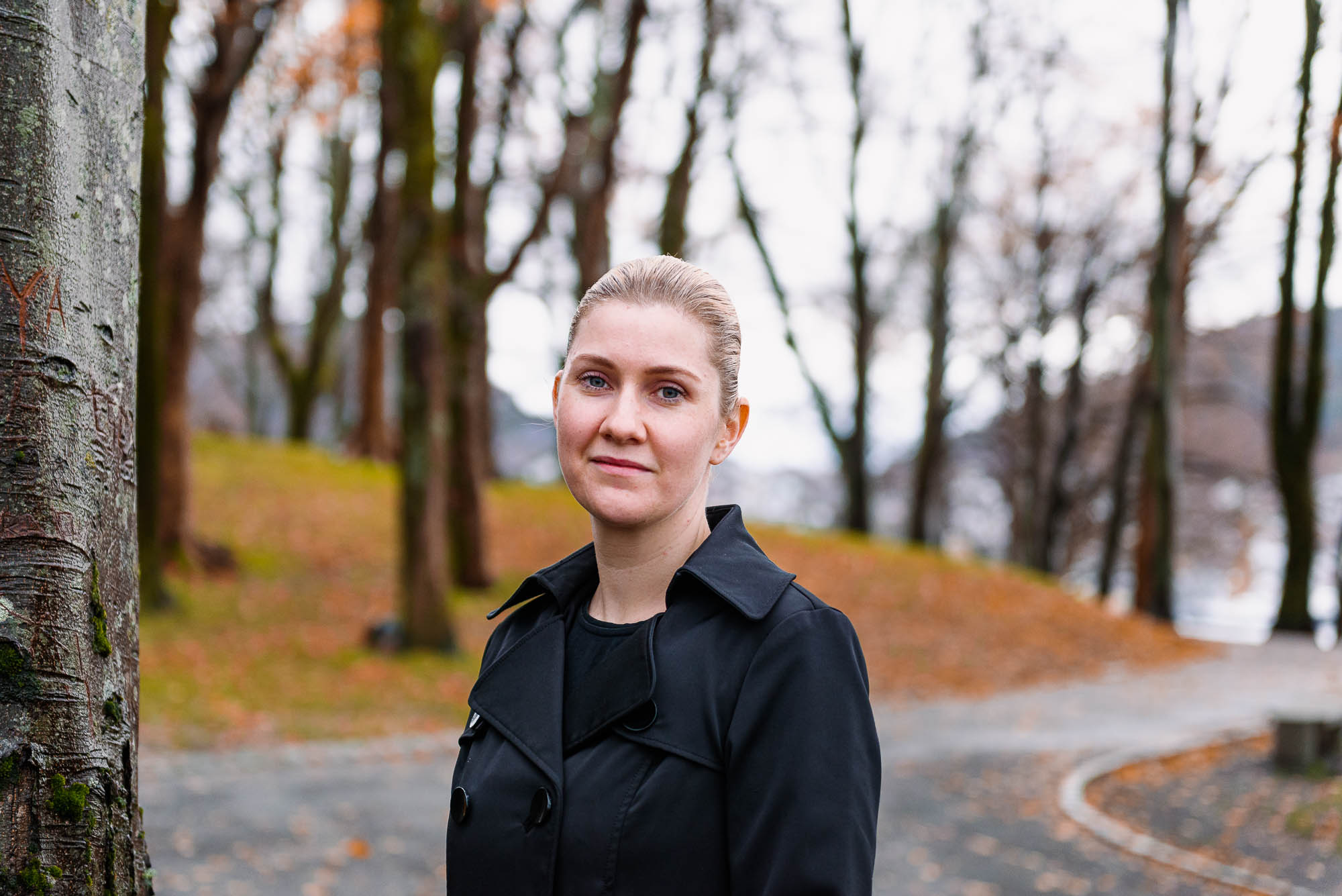 kvinne i sort kåpe i en park med høstfarger