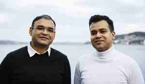 To menn står side om side ute. I bakgrunnen ser man Byfjorden i Bergen