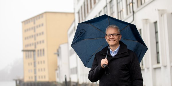 

Nils Gunnar står under paraply og smiler.