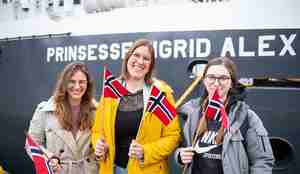 Tre unge kvinner vifter med norske flagg.