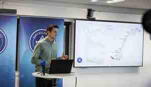 foto av mann ved podie og presentasjon