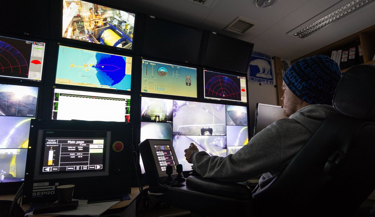 En mann sitter i et kontrollrom med mange skjermer og styrer undervannsroboten.
