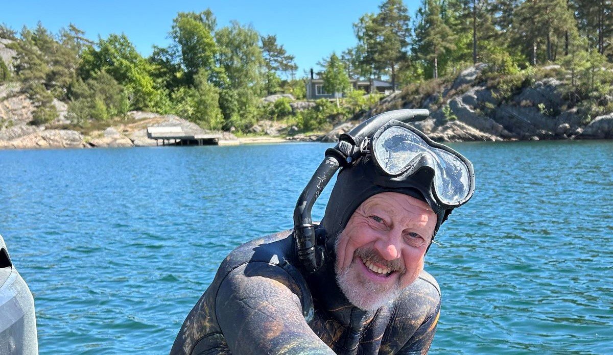 
Foto av en blid havforsker Stein Mortensen med sjø, svaberg og skog i bakgrunnen
