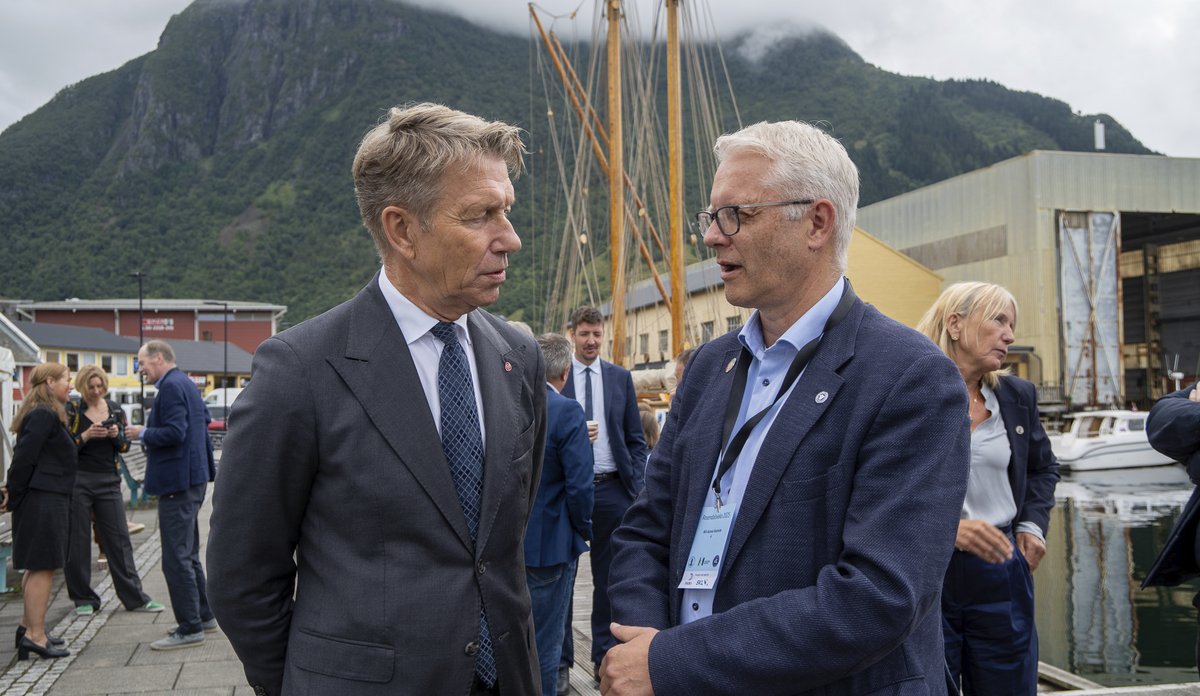 To menn i dress snakker sammen på en kai