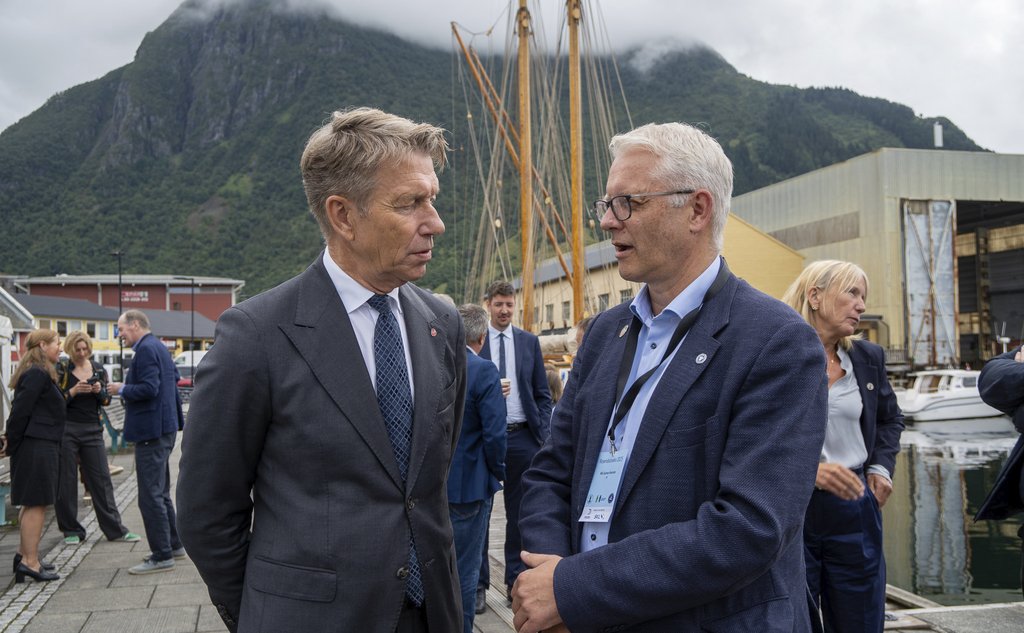 To menn i dress snakker sammen på en kai