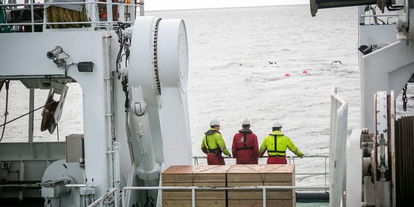 

Three people in overalls on the deck of a large boat. 