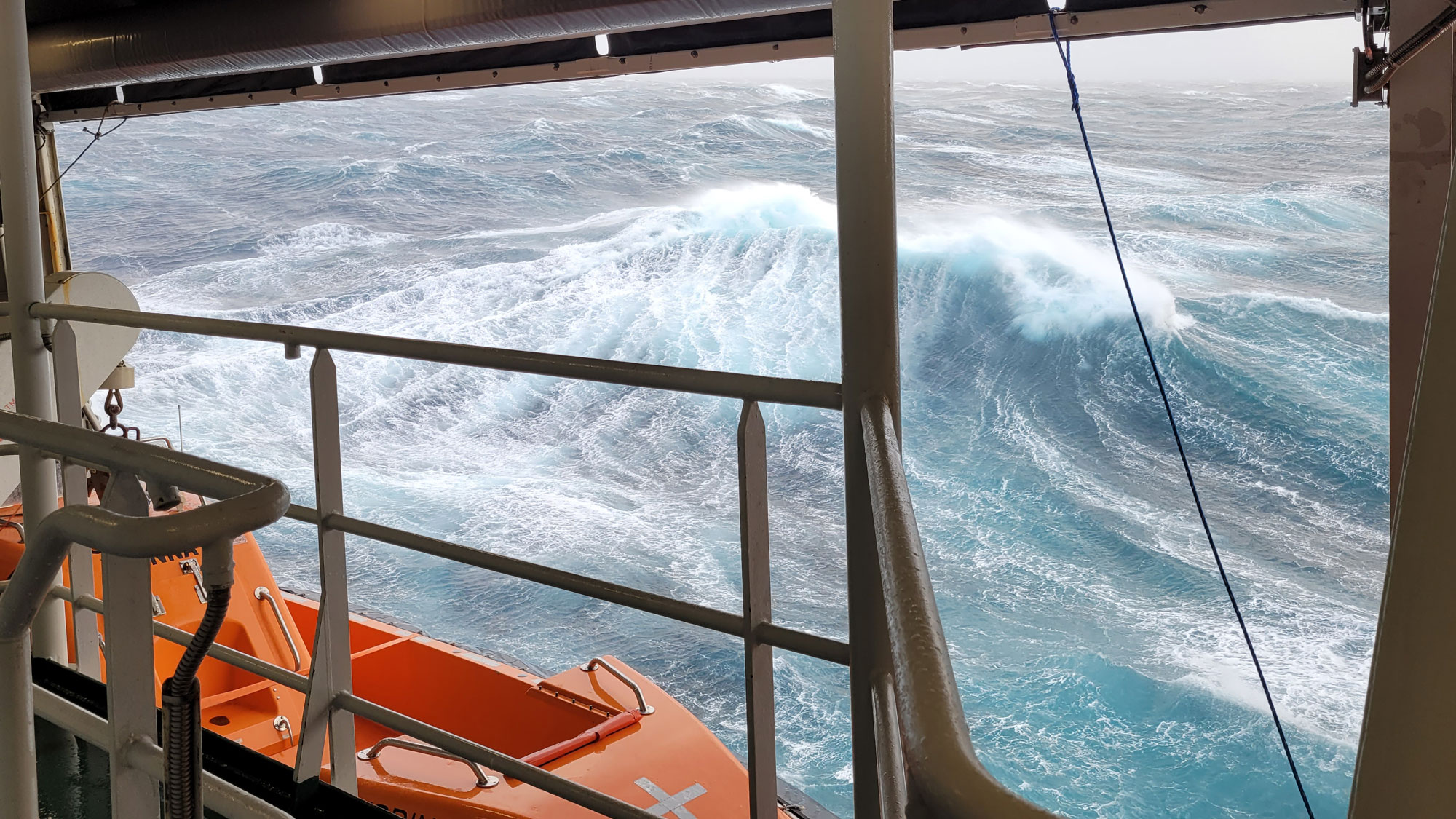 Foto av høye bølger med hvitt skum på.