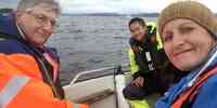 To menn og ei kvinne i småbåt på fjorden.