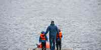

Mann og to barn står med ryggen til kamera på en brygge og fisker.