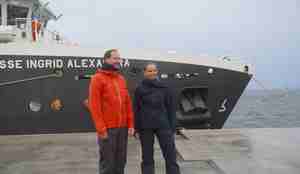 foto av en mann og en kvinne som står foran baugen på et skip