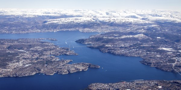 

Fjordlandskap med snøkledde fjell i bakgrunnen, sett fra et fly 
